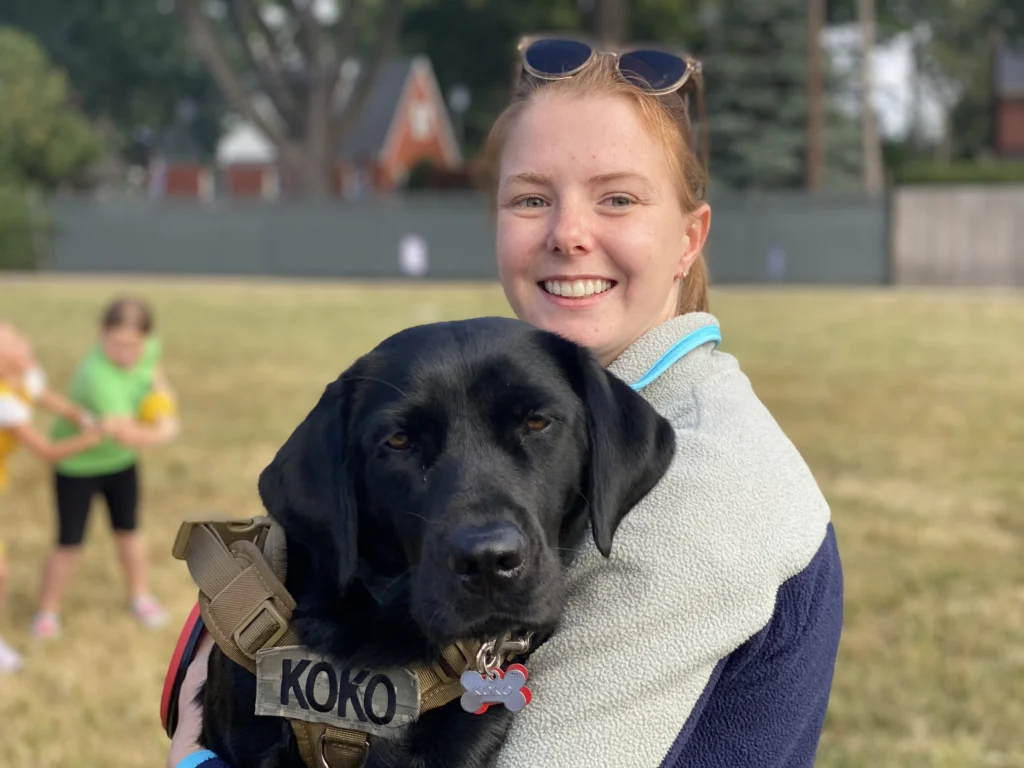 Jessie holding Koko, a black labrador service dog