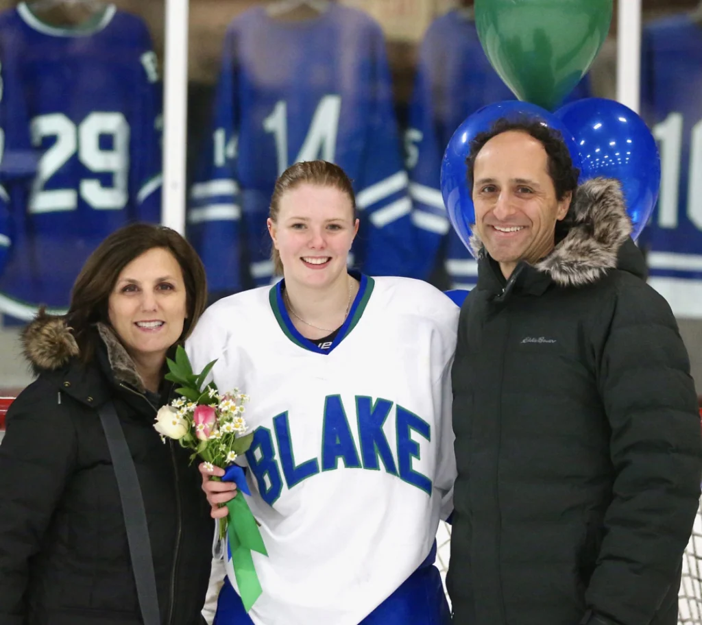 Jessie in a hockey jersey posing with family