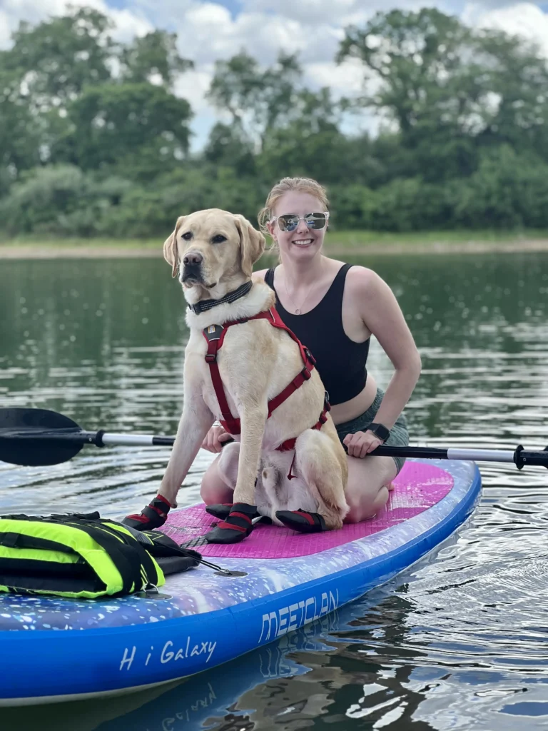 Jessie and service dog looking at camera from paddle board on a lake