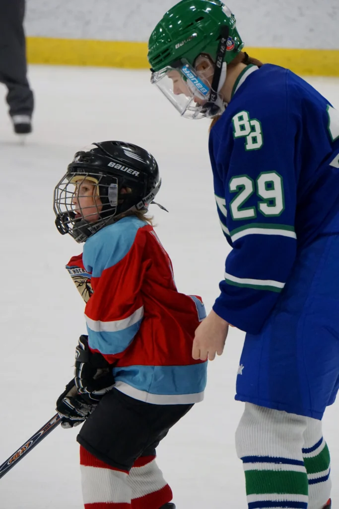Jessie coaching a child in a hockey rink