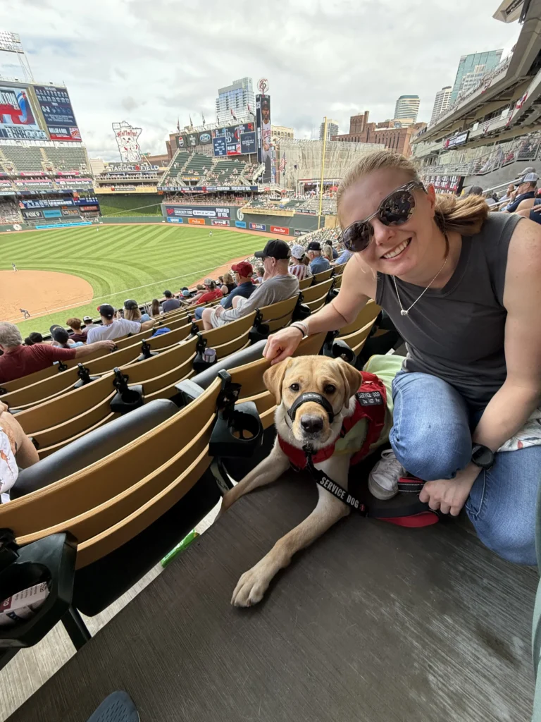 Jessie and service dog looking at camera at a baseball game