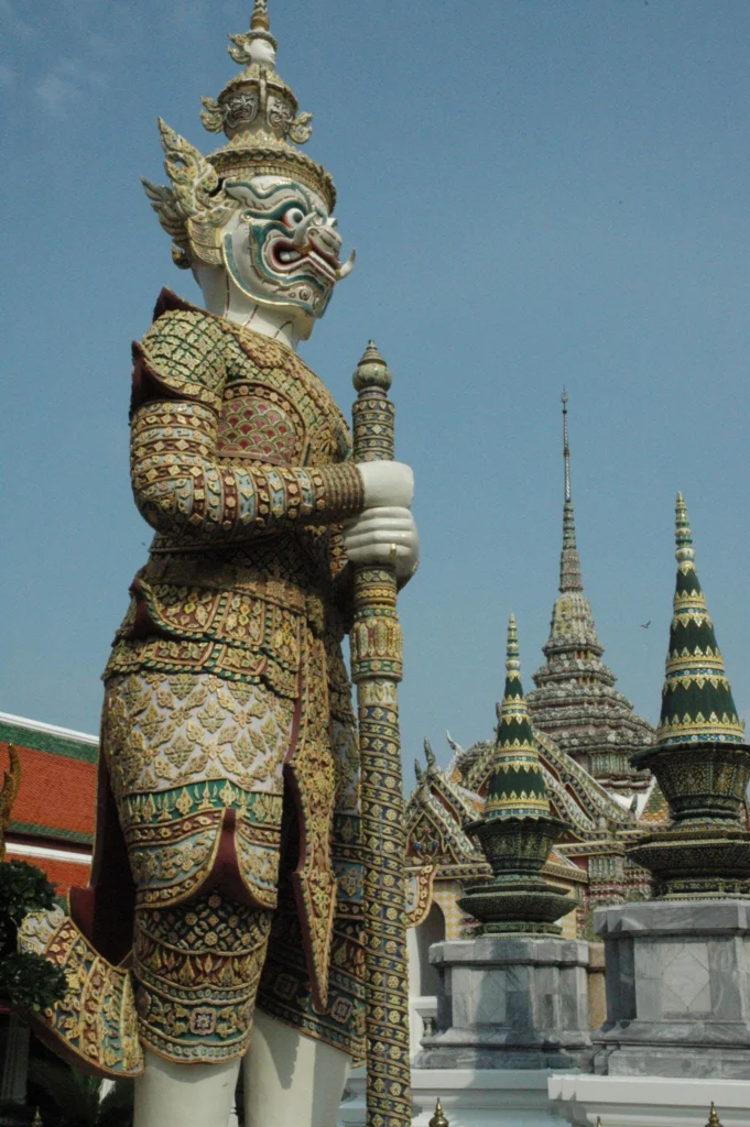 Ornately decorated Thai guardian statue holding a staff at the Grand Palace complex in Bangkok, Thailand.