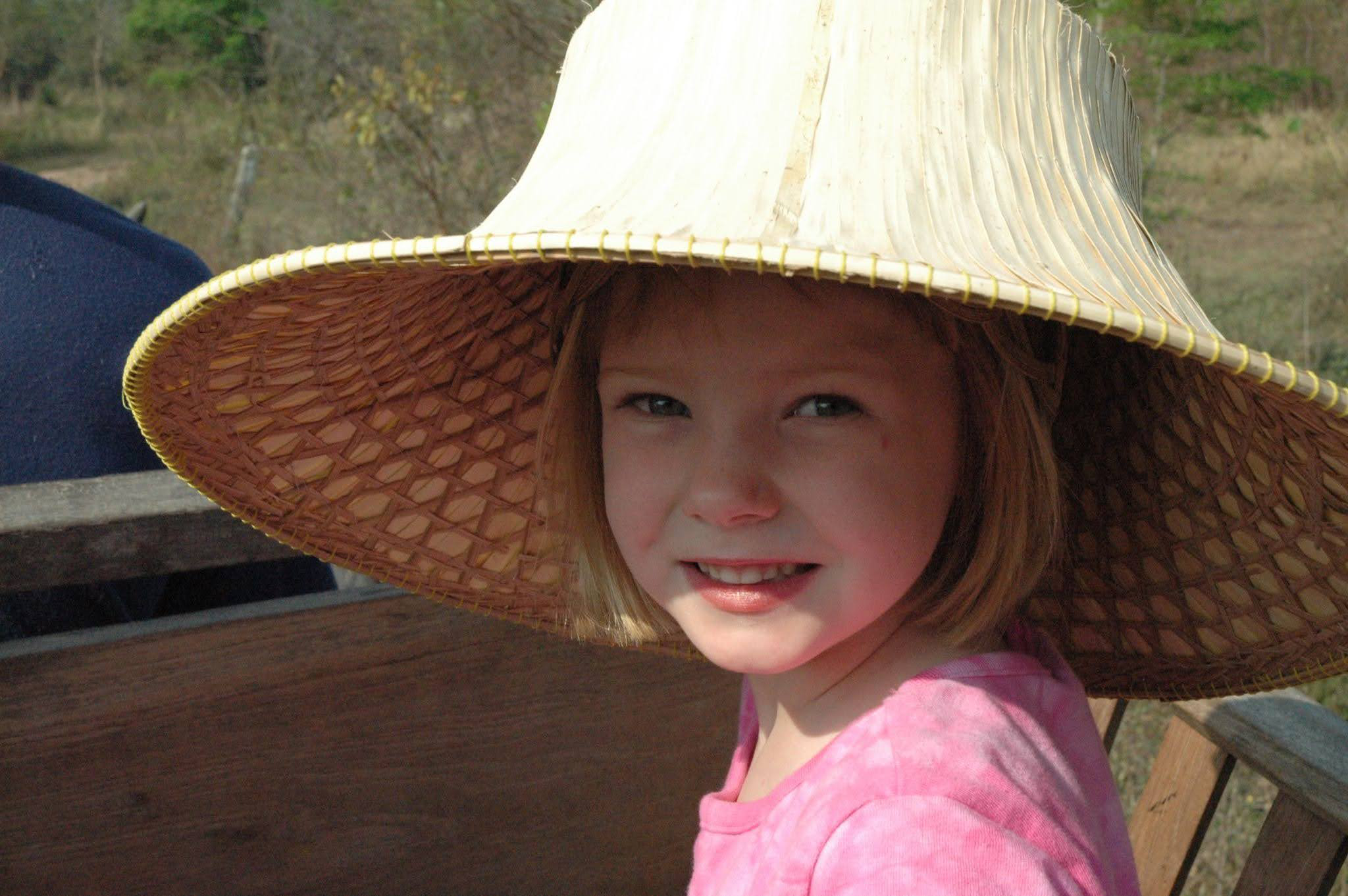 Jessie Rudin as a child wearing a traditional wide-brimmed straw hat during a trip to Thailand.